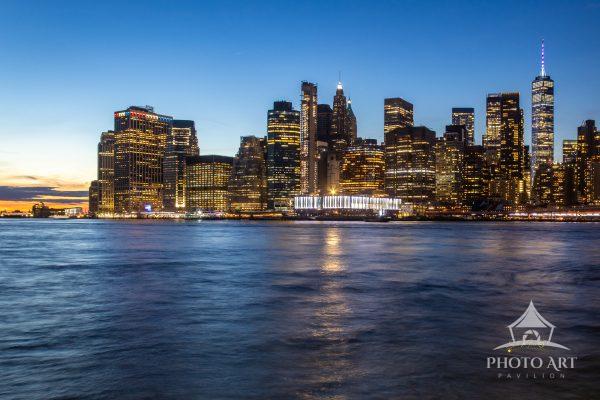 The image captures a stunning twilight view of the New York City skyline, showcasing a blend of
