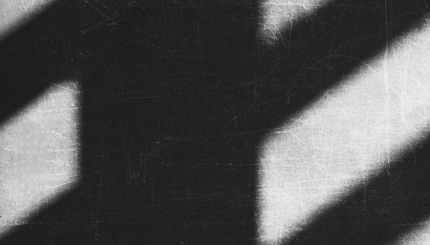 Shadows streak across the frame in quiet geometry; one in a steady horizontal band, others slipping