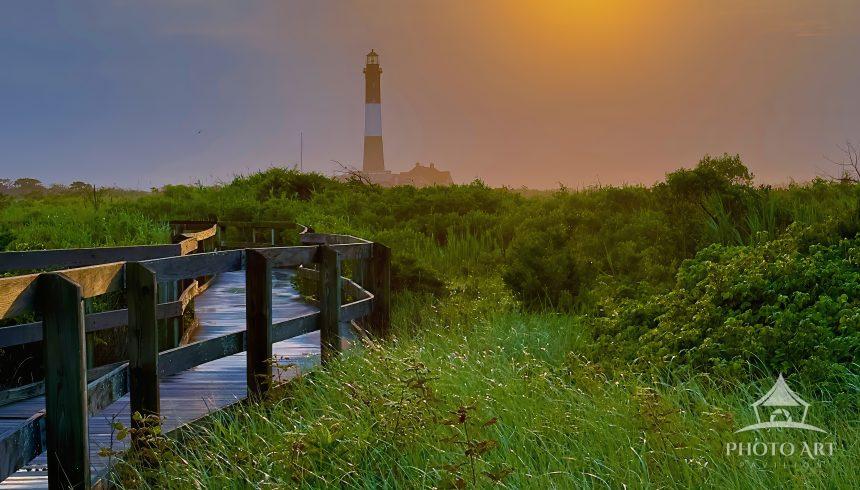 As the sun rises over the Fire Island National Seashore, a warm golden glow bathes the historic 1858