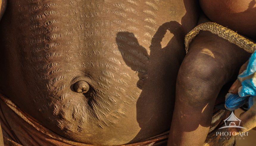 Beautiful, decorative, scarification on the stomach of a young mother holding her child