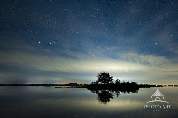 Day gives way to a star filled night over calm waters