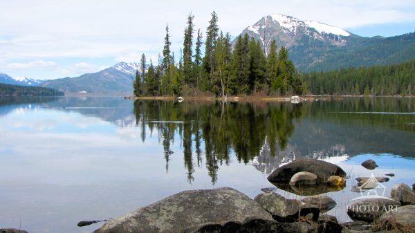 Island trees and mountains reflecting off a Lake calm and clear as glass. Lake Wenatchee