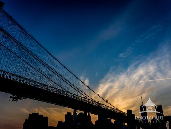 At DUMBO Brooklyn, the sky holds a delicate tension—warm amber dissolving into deep blue—framing the