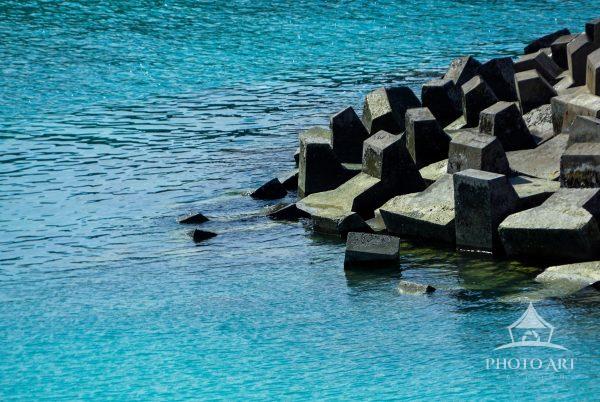 Clear blue waters meet sculpted stone along the Bali coast. A calm, sunlit moment where the sea