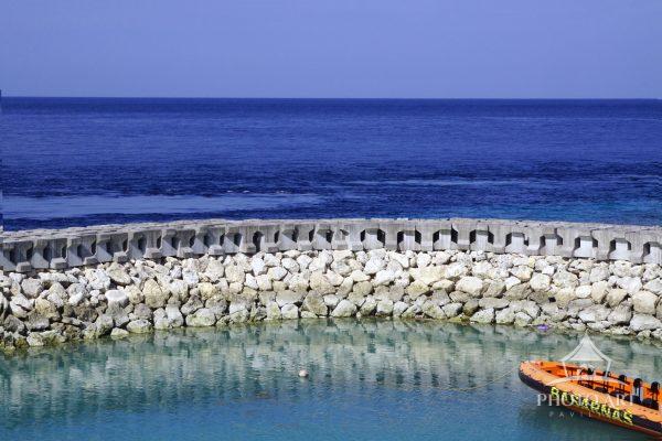 A sculpted line of concrete forms anchors the foreground, its repeating geometry creating a quiet