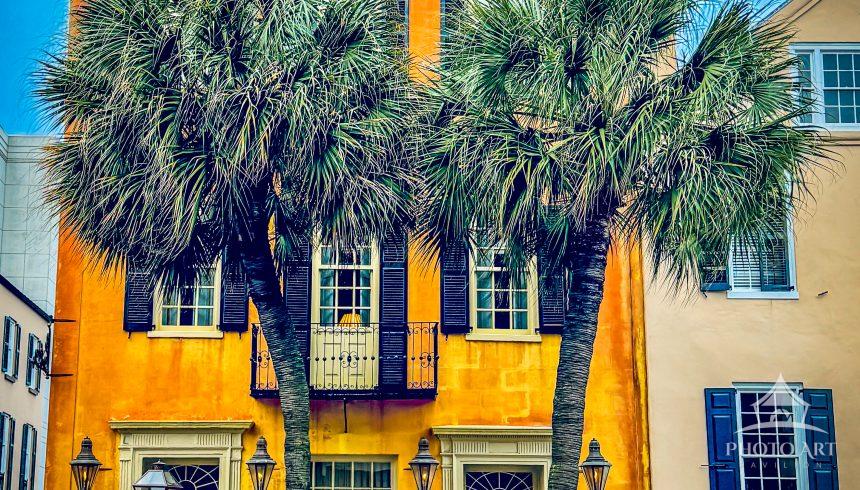 A vibrant townhouse framed by two tall palm trees, classic windows, shutters and lanterns convey