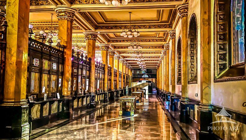 A grand historic building interior featuring polished marble floors, ornate gilded columns, high