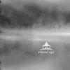 A blanket of fog drifts across still waters in this moody black-and-white scene. Dark silhouettes of