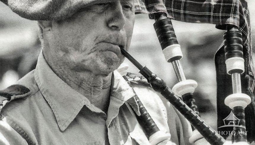 This striking, close-up monochrome portrait captures an elderly bagpiper fully immersed in his