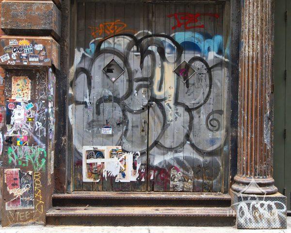 A gritty, textured closeup of an NYC alleyway wall densely covered in vibrant street art stickers,