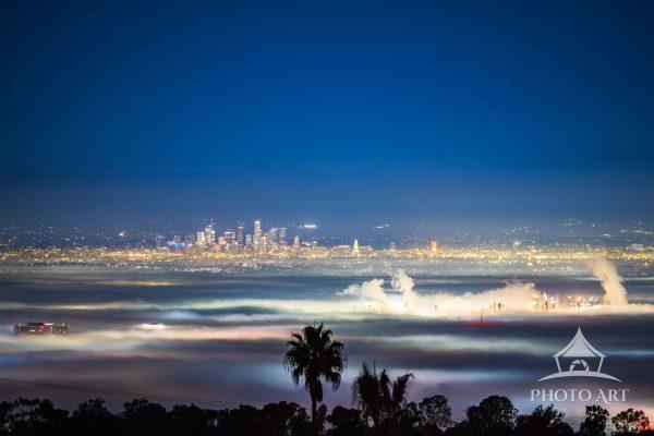 City lights, building tops, and an oil refiner poke through the marine layer in the Los Angeles