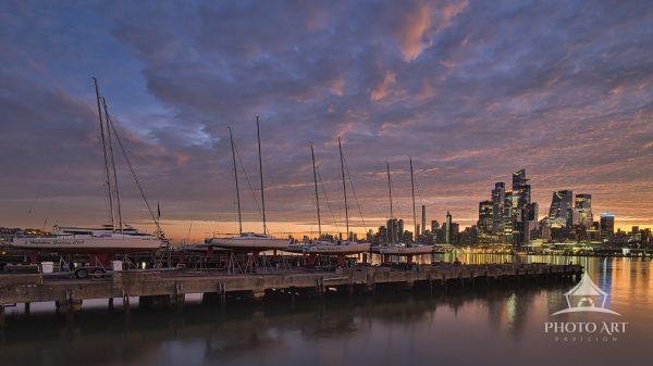 This sophisticated fine art photograph showcases a row of docked sailboats against the glowing